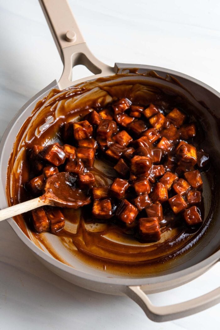 Baked tofu cubes in thick brown sauce in a pan.