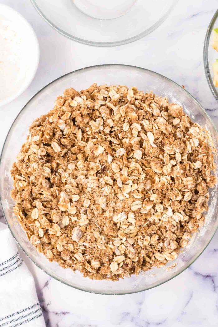 Oatmeal, brown sugar, butter and flour mixed up in a glass mixing bowl.