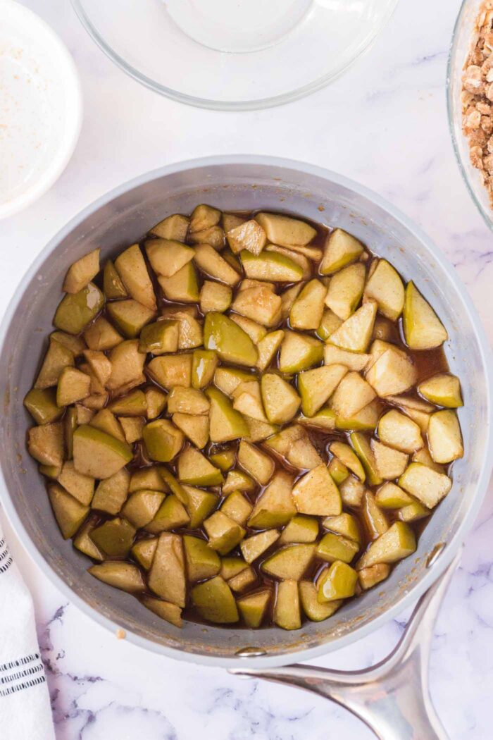 Diced apples cooking in pot with lemon juice and spices.