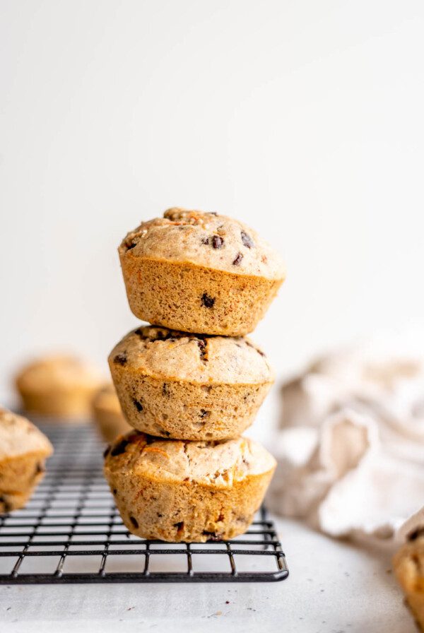 A stack of 3 chocolate chip muffins on a cooling rack.