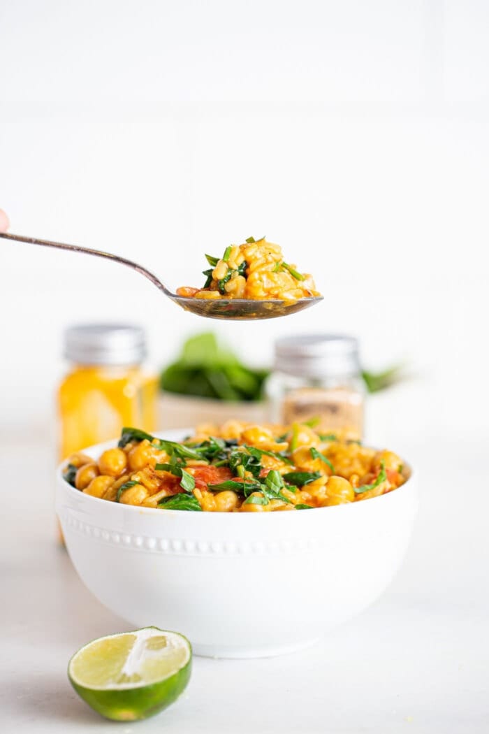Taking a spoonful of rice, chickpea and spinach stew.