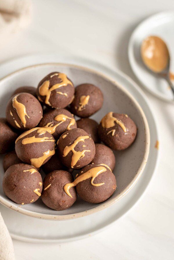 Chocolate energy balls drizzled with peanut butter in a bowl.