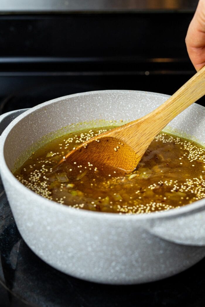 A pot of broth with lentils and quinoa simmering on a stovetop.