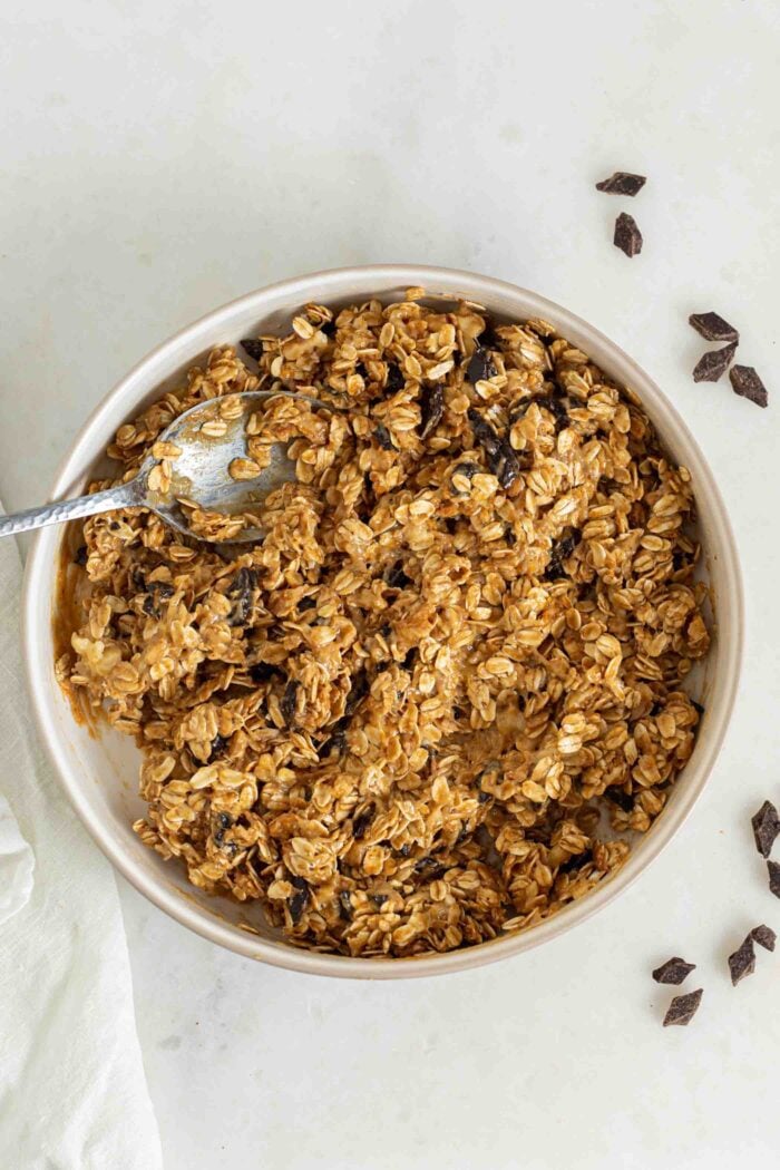 Thick oatmeal chocolate chip cookie dough in a bowl with a spoon.