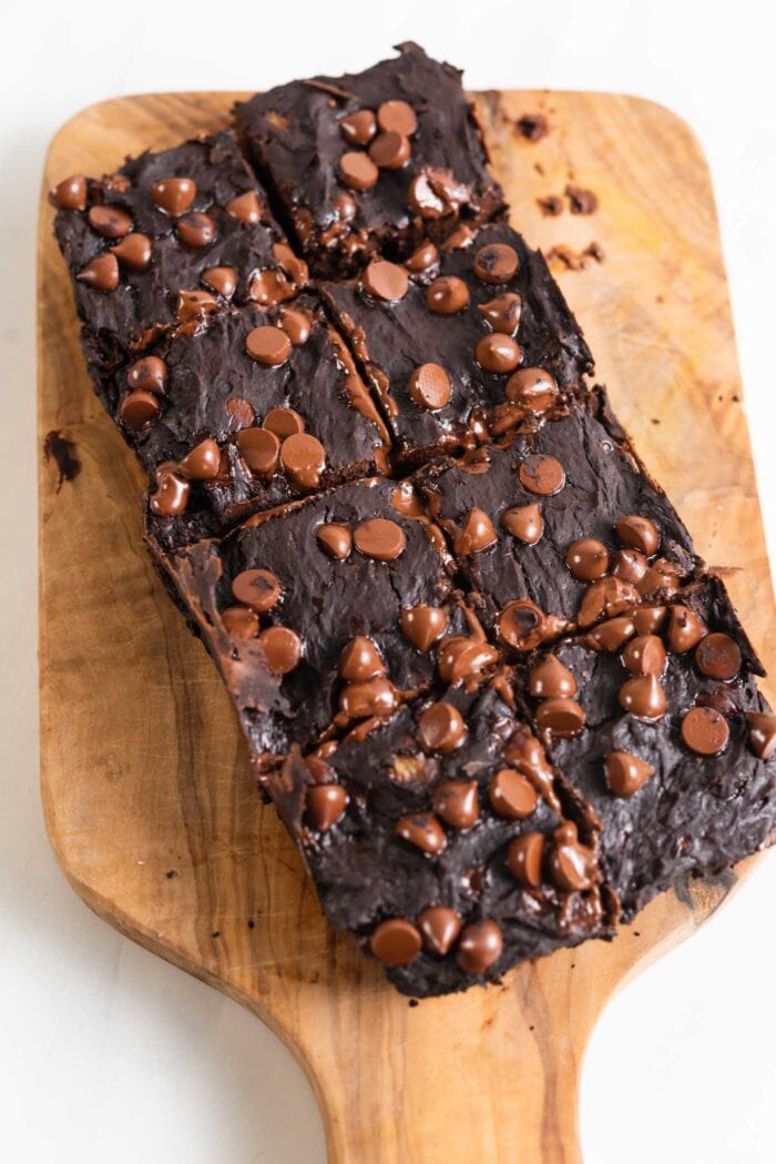 A tray of chocolate chip brownies cut into 8 pieces on a cutting board.