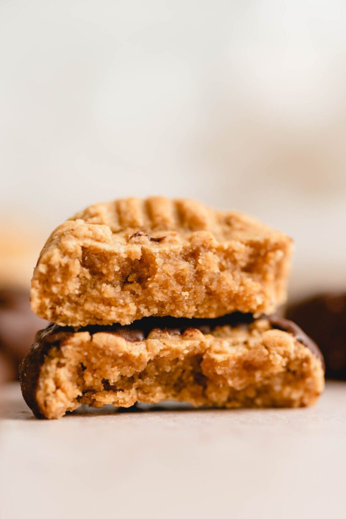 Two halves of a chocolate-coated peanut butter cookie stacked on top of each other so you can see the inside texture of the cookie.