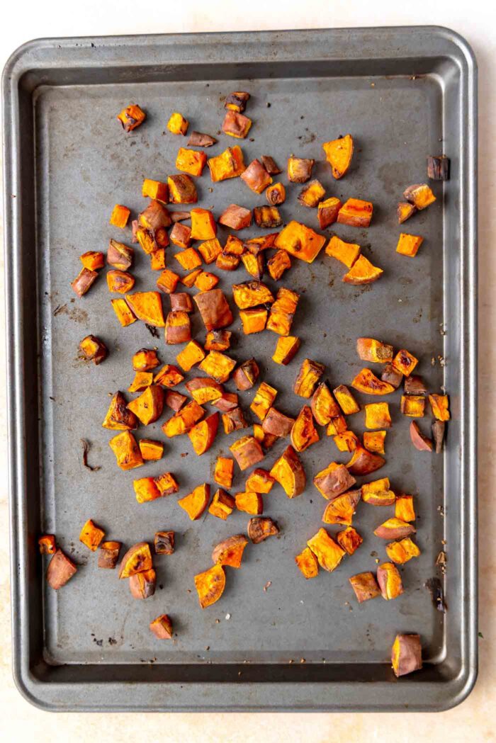Small cubes of roasted sweet potato on a baking tray.
