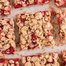 An overhead close up of a number of strawberry oat bars with an oatmeal crumble topping.