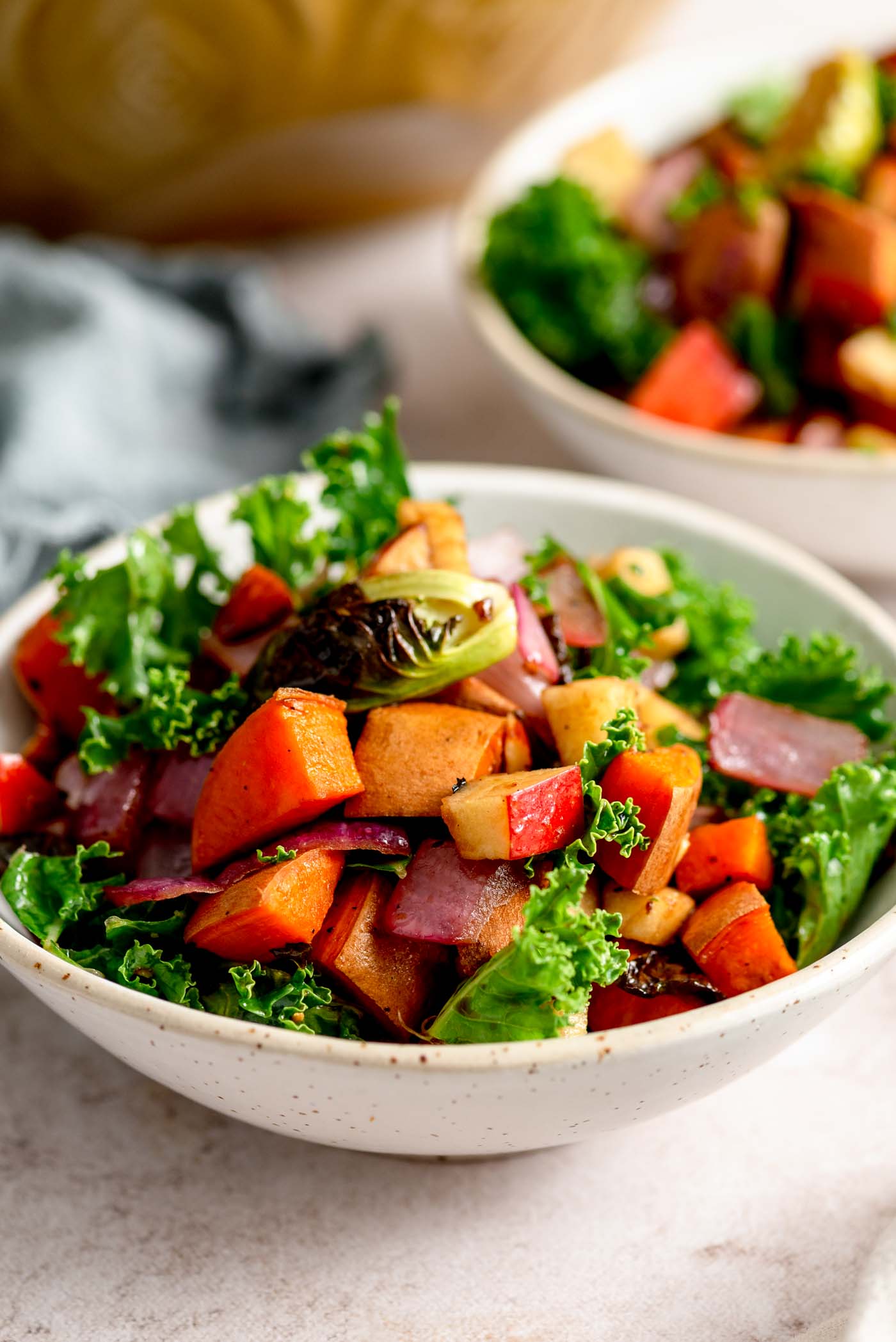 Roasted vegetable kale apple salad with sweet potato in a small bowl.