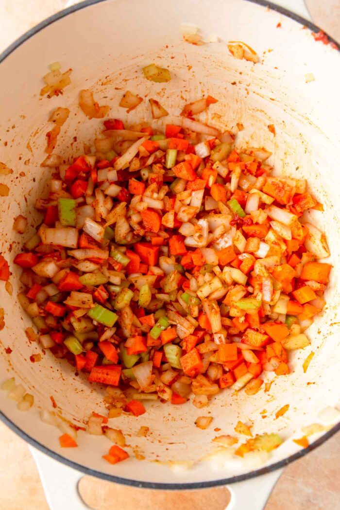Celery, onion, carrot, garlic and spices cooking in a large pot.