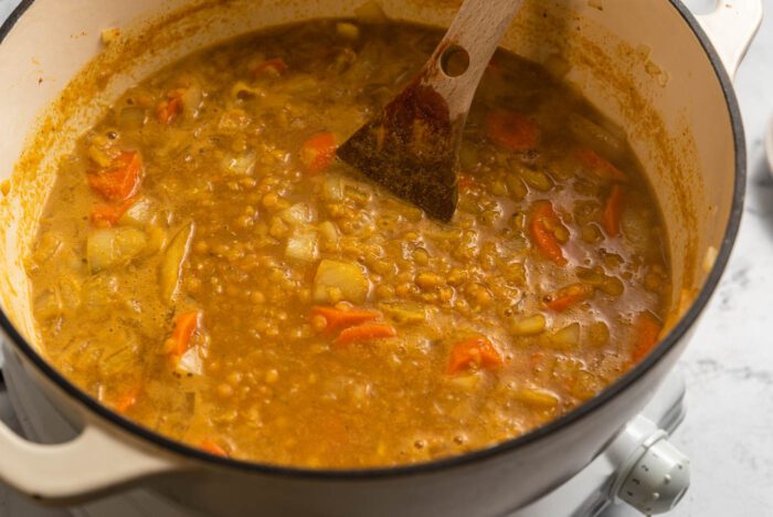 Lemon red lentil soup with carrots in a large soup pot on a small hot plate.