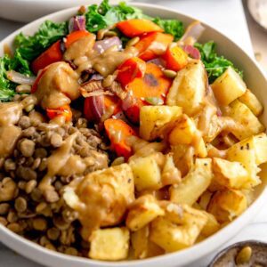 Healthy vegan bowl with roasted potatoes, roasted onion and carrot, lentils, kale and gravy.