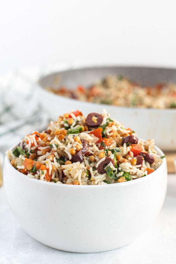 Bowl of rice and lentils with spinach and olives.
