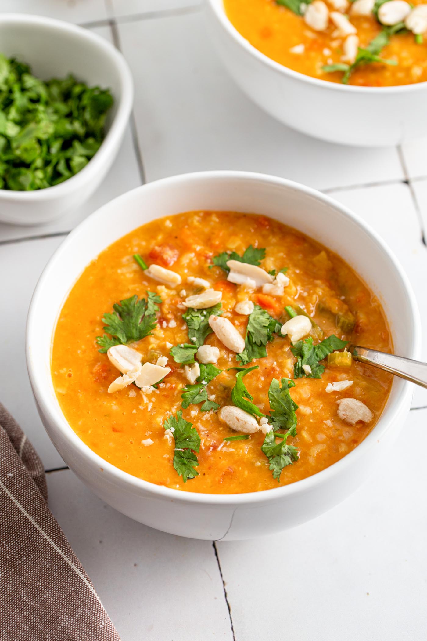 Bowl of mulligatawny soup topped with fresh herbs and peanuts.
