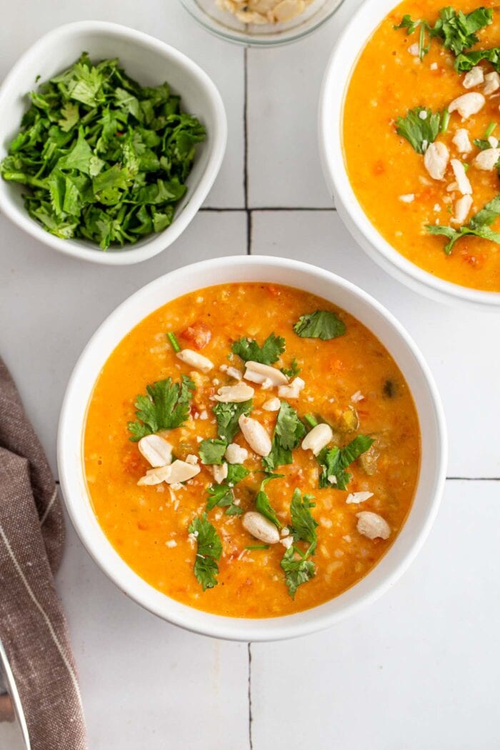 Bowl of mulligatawny soup topped with fresh herbs and peanuts.