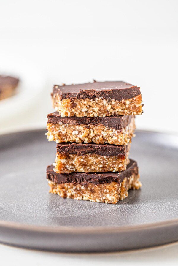 Stack of 4 chocolate coated cashew bars on a plate.