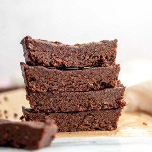 Stack of 4 chocolate protein bars on parchment paper on a marble cutting board.
