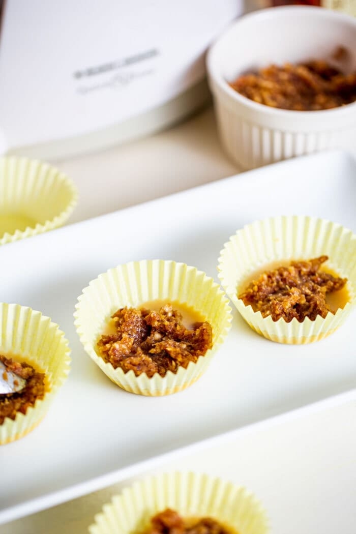 Date paste in 3 muffin liners on a small white plate.