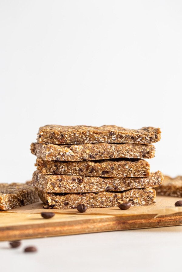 Stack of 4 energy bars on a cutting board. Coffee beans scattered around.