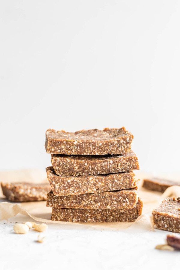 Stack of 5 vegan paleo energy bars sitting on parchment paper against a white background.