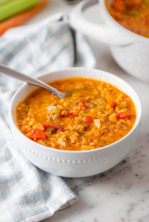 A bowl of red lentil soup on a marble counter top.