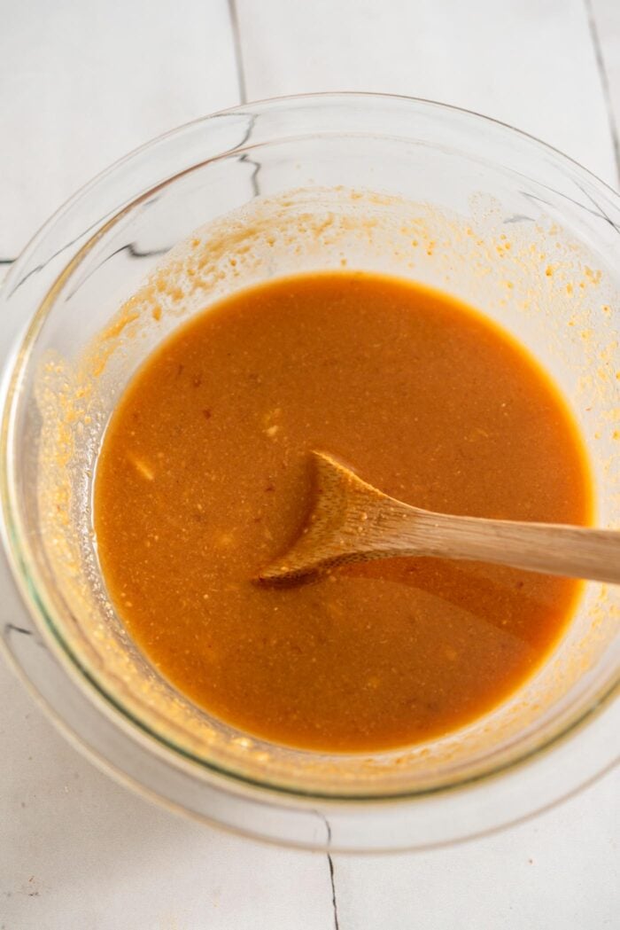 Miso tahini sauce mixed together in a small glass bowl. A small wooden spoon rests in the bowl.