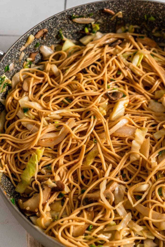 Ramen noodles with cabbage, green onion, mushrooms and sauce in a large skillet.