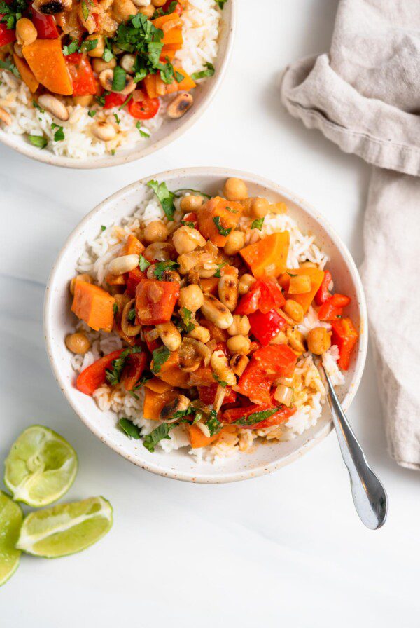 Overhead view of a bowl of sweet potato and chickpea curry topped with peanuts and over rice.