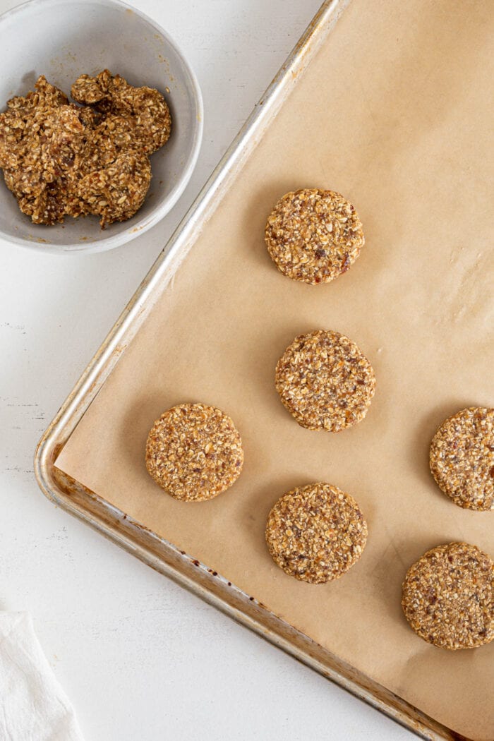 Bowl of cookie dough beside a baking tray of cookies.