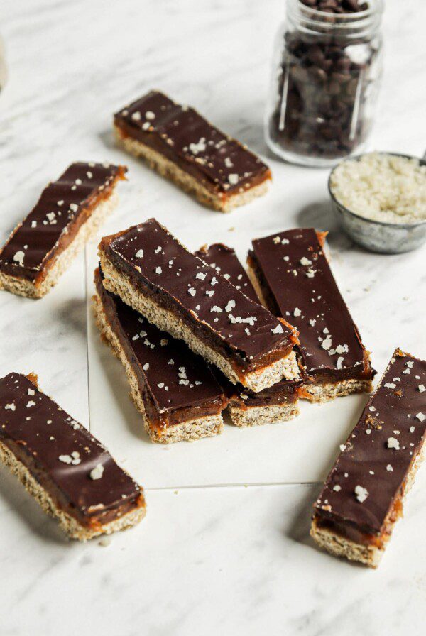 A number of homemade Twix candy bars on a marble surface lined with parchment paper.