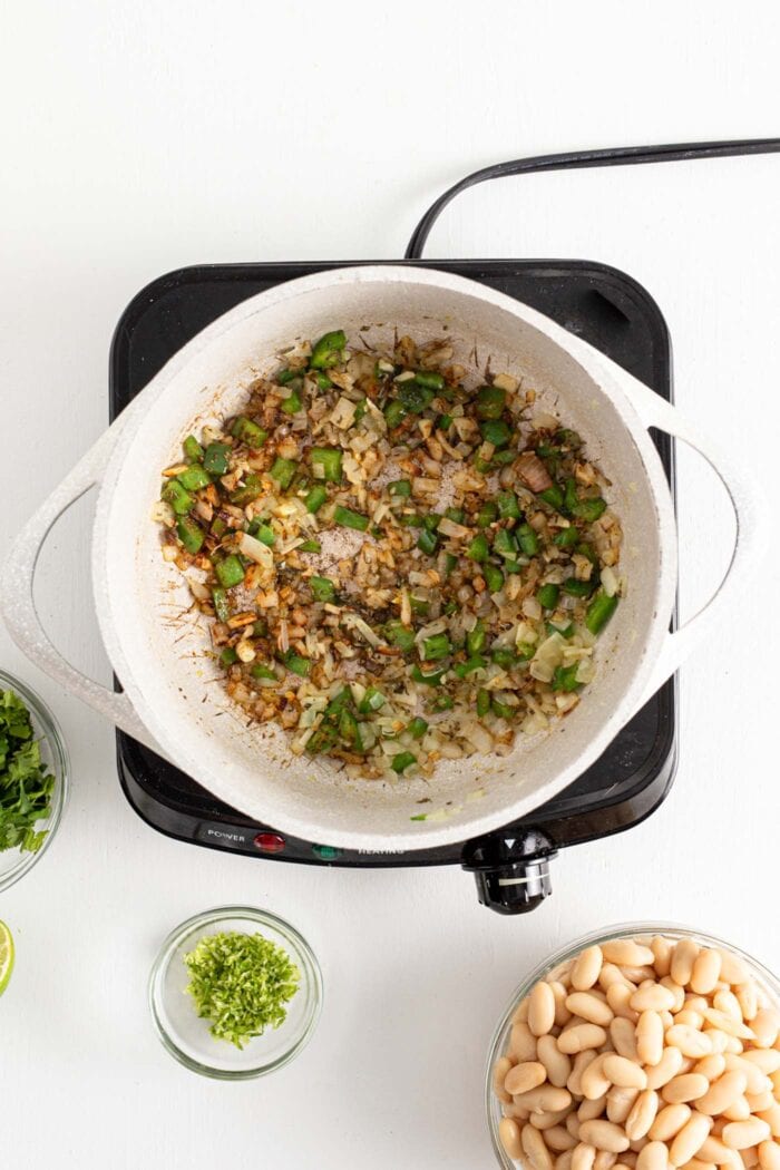 Jalapeno, garlic, spices and onion cooking in a large soup pot.
