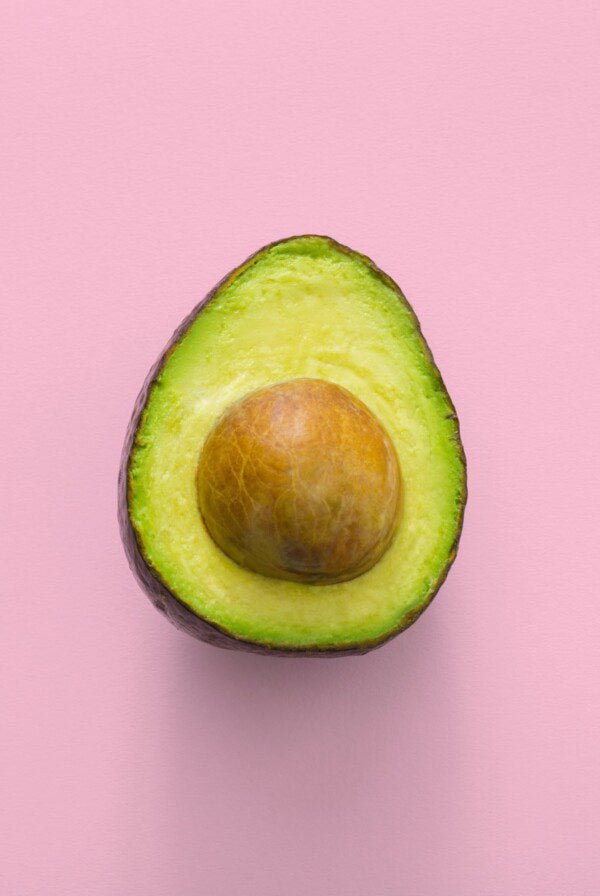 Ripe cut avocado on a pink background.
